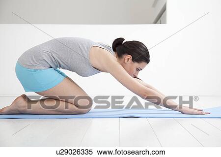 Woman stretching on yoga mat View Large Photo Image Stock Photography - Woman stretching on yoga mat. Fotosearch