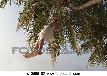 Stock Image - Woman swinging from tree. Fotosearch