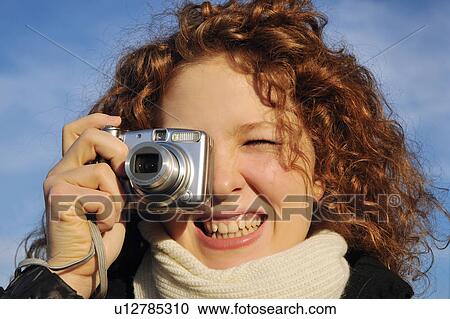 Stock Image - Woman taking a picture outdoors. Fotosearch
