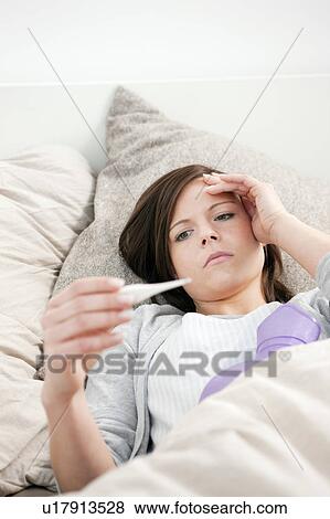 Woman taking her temperature in bed View Large Photo Image Stock Photo - Woman taking her temperature in bed. Fotosearch