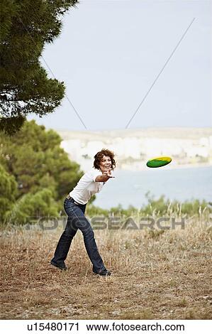 Stock Image - Woman throwing frisbee outdoors. Fotosearch