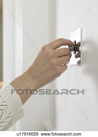 Stock Photo - Woman turning on light switch. Fotosearch