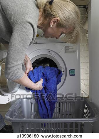 Stock Image - Woman unloading clothes from dryer. Fotosearch