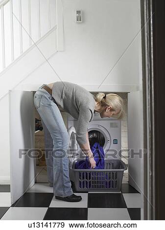 Stock Photo - Woman unloading clothes from dryer. Fotosearch
