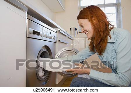 Stock Image - Woman unloading washing machine. Fotosearch