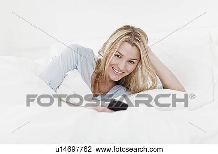 Stock Image - Woman using cell phone in bed. Fotosearch