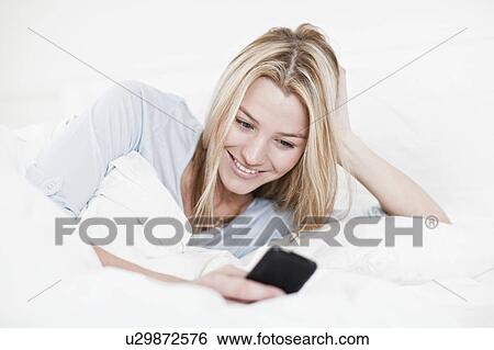 Woman using cell phone in bed View Large Photo Image Stock Photograph - Woman using cell phone in bed. Fotosearch