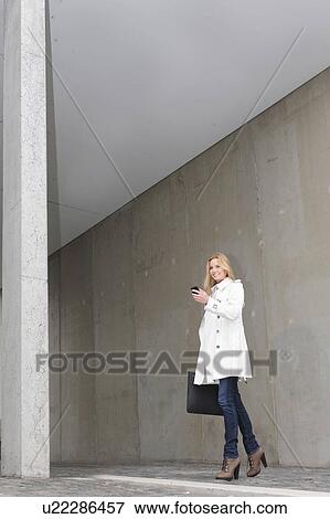 Stock Photo - Woman using cell phone on city street. Fotosearch