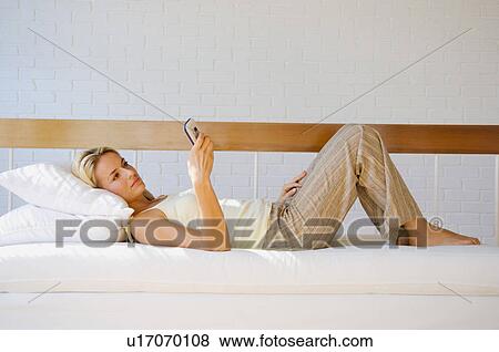 Woman using cell phone on sofa View Large Photo Image Stock Photo - Woman using cell phone on sofa. Fotosearch
