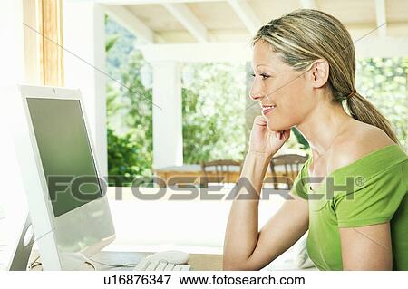Stock Photo - Woman using computer at desk. Fotosearch