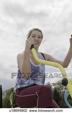 Woman using exercise bike outdoors View Large Photo Image Stock Image - Woman using exercise bike outdoors. Fotosearch