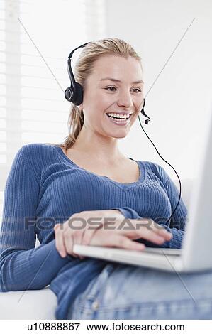 Woman using headset on laptop View Large Photo Image Stock Photo - Woman using headset on laptop. Fotosearch