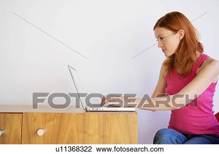 Woman using laptop at desk View Large Photo Image Stock Image - Woman using laptop at desk. Fotosearch