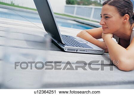 Woman using laptop by pool View Large Photo Image Stock Image - Woman using laptop by pool. Fotosearch
