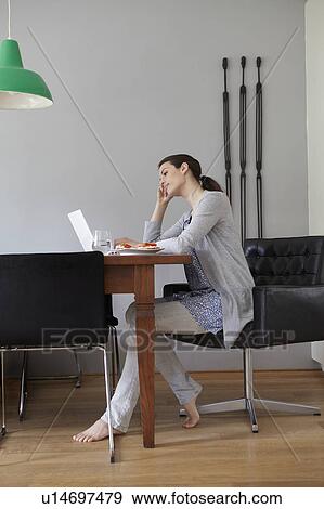 Stock Photo - Woman using laptop in dining room. Fotosearch