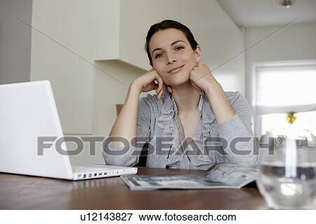 Stock Photo - Woman using laptop in living room. Fotosearch