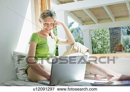 Woman using laptop in nook View Large Photo Image Stock Photo - Woman using laptop in nook. Fotosearch