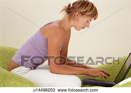 Woman using laptop on couch View Large Photo Image Stock Image - Woman using laptop on couch. Fotosearch