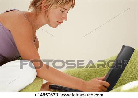 Woman using laptop on couch View Large Photo Image Stock Image - Woman using laptop on couch. Fotosearch