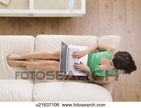 Stock Photograph - Woman using laptop on couch. Fotosearch