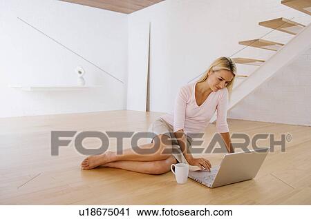 Stock Image - Woman using laptop on floor. Fotosearch