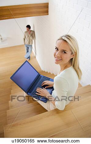 Stock Photography - Woman using laptop on stairs. Fotosearch