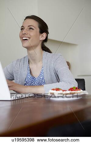Woman using laptop with plate of food View Large Photo Image Stock Photo - Woman using laptop with plate of food. Fotosearch