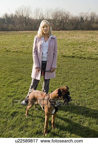 Stock Photo - Woman walking dog in field. Fotosearch