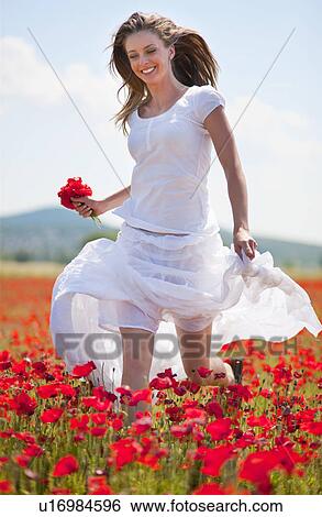 Stock Photograph - Woman walking in field of flowers. Fotosearch