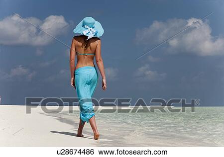 Stock Photograph - Woman walking on tropical beach. Fotosearch