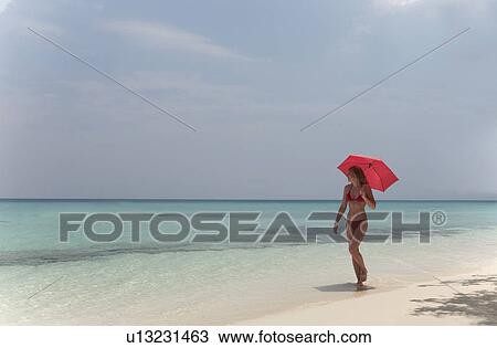 Woman walking with umbrella on beach View Large Photo Image Stock Image - Woman walking with umbrella on beach. Fotosearch