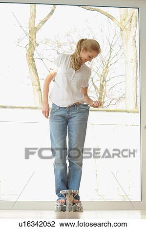 Woman wearing large jeans on scale View Large Photo Image Stock Image - Woman wearing large jeans on scale. Fotosearch