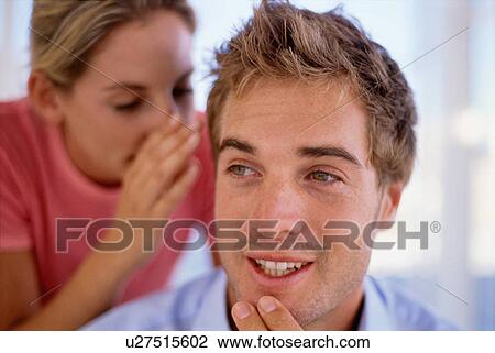 Stock Image - Woman whispering in man’s ear. Fotosearch