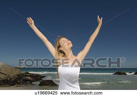 Stock Photography - Woman with arms outstretched on beach. Fotosearch