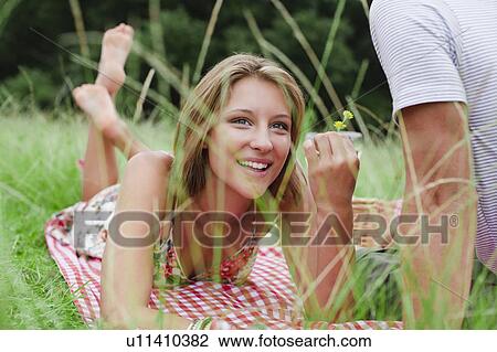 Stock Image - Woman with flower on picnic blanket. Fotosearch