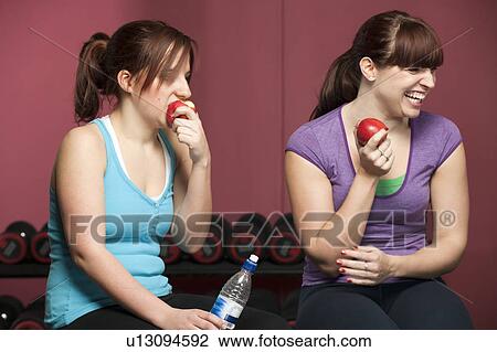 Stock Image - Women eating apples in gym. Fotosearch