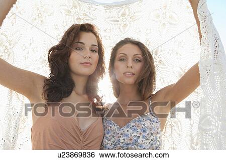 Stock Photograph - Women holding blanket over them. Fotosearch