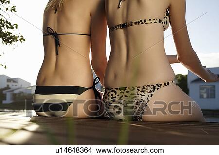 Picture - Women in bikinis sitting on deck. Fotosearch