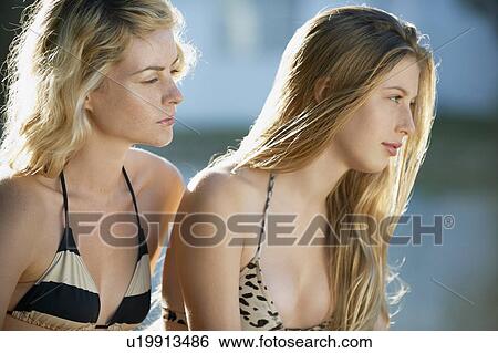 Stock Photograph - Women in bikinis sitting together. Fotosearch