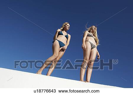Women in bikinis standing on wall View Large Photo Image Stock Image - Women in bikinis standing on wall. Fotosearch