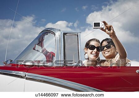 Stock Photo - Women taking picture of themselves. Fotosearch