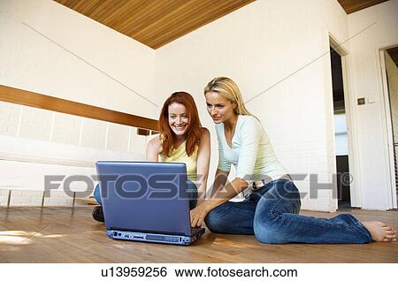 Women using laptop on floor together View Large Photo Image Stock Photograph - Women using laptop on floor together. Fotosearch