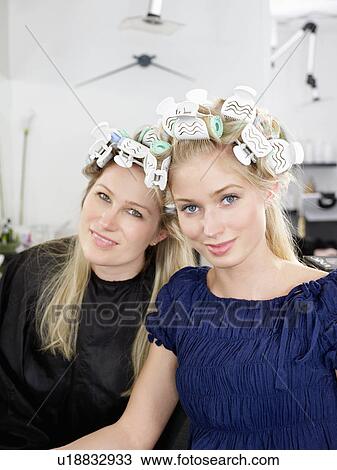Stock Image - Women wearing rollers in salon. Fotosearch