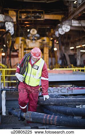 Worker carrying rope on oil rig View Large Photo Image Stock Photography - Worker carrying rope on oil rig. Fotosearch
