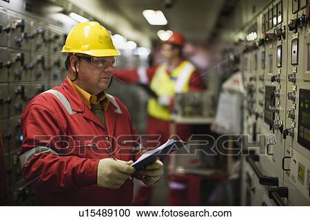 Stock Image - Worker checking machinery. Fotosearch