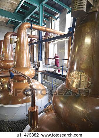 Worker checking stills in distillery View Large Photo Image Stock Image - Worker checking stills in distillery. Fotosearch
