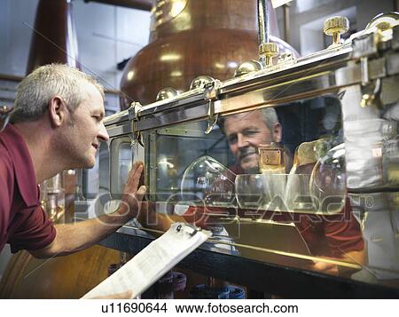 Worker checking whisky in distillery View Large Photo Image Picture - Worker checking whisky in distillery. Fotosearch