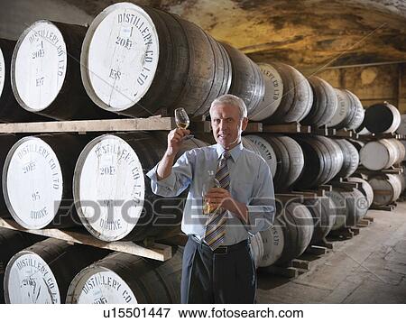Stock Photo - Worker checking whisky in distillery. Fotosearch