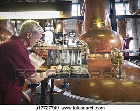 Worker checking whisky in distillery View Large Photo Image Stock Photo - Worker checking whisky in distillery. Fotosearch