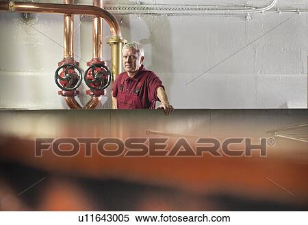 Stock Photography - Worker checking whisky in distillery. Fotosearch